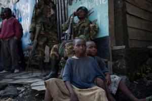 Två barn sitter framför M23-rebeller vid en butik i staden Sake, 26 kilometer väster om Goma.